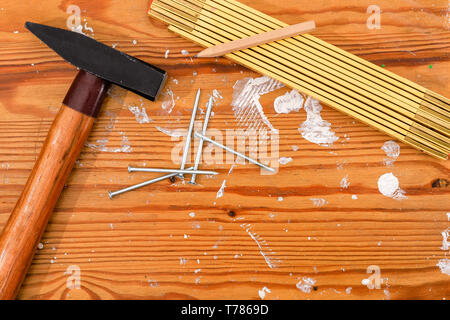 Hammer, Zollstock und Nägel auf eine gefleckte Holz. Stockfoto