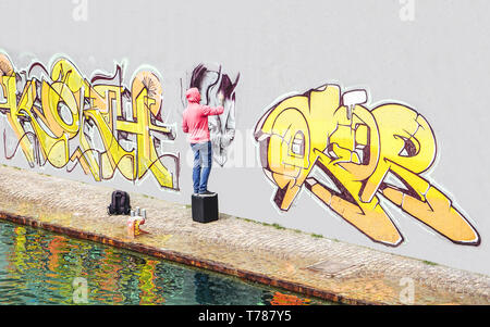 Street Graffiti Künstler Malen mit einem Color Spray kann ein Graffiti an der Wand in der Stadt - Begriff der zeitgenössischen Kunst lifestyle Stockfoto