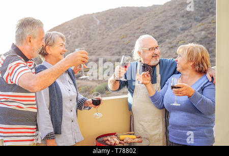 Happy senior Freunden Spaß haben, trinken Rotwein am Grill auf der Terrasse - reife Menschen speisen und zusammen lachen auf dem Dach Stockfoto