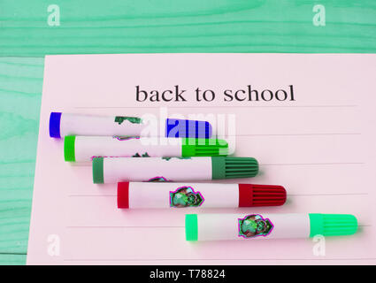 Zurück zu Schule. Blatt Papier mit Text und farbigen Markierungen auf einer grünen Holz- Hintergrund, Ansicht von oben. Stockfoto