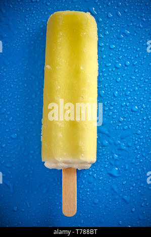 Gelbe Eis am Stiel oder Eis pop auf einem blauen Hintergrund mit Wassertropfen Stockfoto