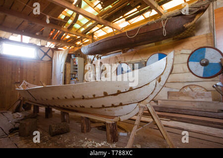 Handgefertigten Holz- Boot in der Scheune, Werkzeuge und reenactor Schilde auf Hintergrund Stockfoto