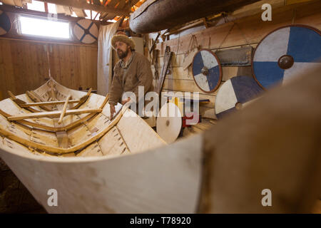 Handgefertigten Holz- Boot in der Scheune und reenactor in mittelalterlichen Kleidern Stockfoto