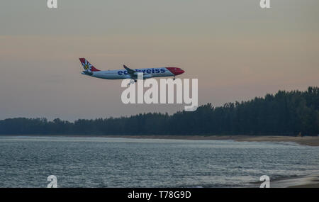 Phuket, Thailand - Apr 4, 2019. HB-JMD Edelweiss Air Airbus A340-300 fliegen über den Sandstrand auf wunderschönen Sonnenaufgang Landschaft auf der Insel Phuket, Thailan Stockfoto