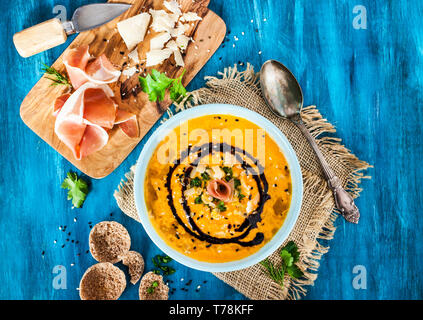 Kürbis creme Suppe Schüssel, serviert mit Sesam, Schinken, Parmesan, Olivenöl, Balsamico und Kräuter Stockfoto