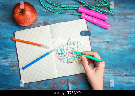 Frau schreiben verschiedene Wörter im Notebook auf hölzernen Tisch. Health Care Konzept Stockfoto