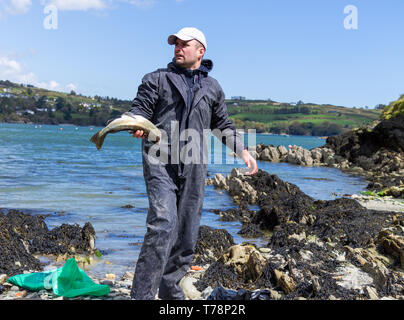 Männliche Meer angler seinen Fang von Fisch Reinigung im Meer Stockfoto