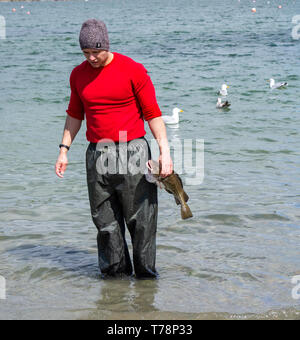 Männliche Meer angler seinen Fang von Fisch Reinigung im Meer Stockfoto