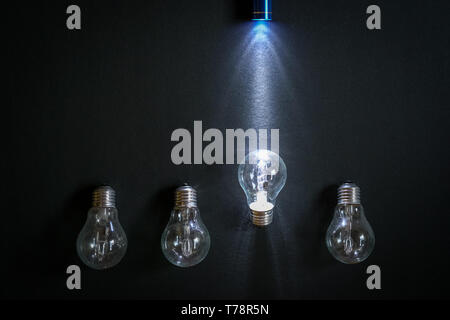 Taschenlampe Leuchten über eine Glühlampe von vier auf schwarzem Hintergrund. Eine Metapher für die Auserwählte oder die richtige Entscheidung. Stockfoto