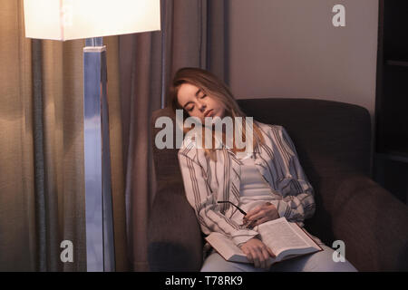 Junge Frau schlafen im Sessel mit Buch Stockfoto
