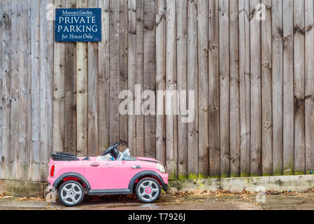 Humorvoll Bild von Spielzeug eines kleinen Kindes Auto unter Privater Parkplatz Schild geparkt. In Cambridge, England, UK gesehen. Stockfoto