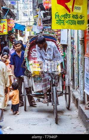 Dhaka, Bangladesch: eine Rikscha Fahrer navigiert durch einen überfüllten Gasse in der Altstadt von Dhaka. Stockfoto