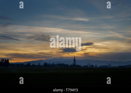 Sonnenuntergang mit verschiedenen Arten von Wolken und ein Berg und Tal Silhouette mit Kirchturm in den österreichischen Alpen in der Steiermark Stockfoto