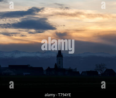 Sonnenuntergang mit verschiedenen Arten von Wolken und ein Berg und Tal Silhouette mit Kirchturm in den österreichischen Alpen Stockfoto