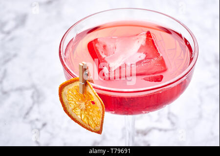 Red Cocktail mit großen Stück Eis dekoriert mit getrockneten Schicht von Orange. Kopieren Sie Platz. Nahaufnahme Stockfoto