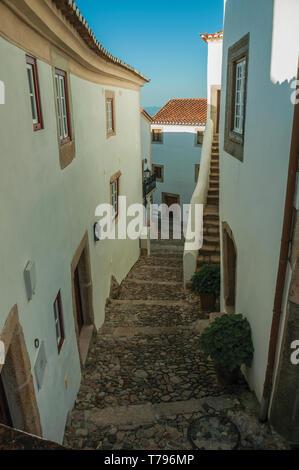 Weiß getünchte Wand an alten Häusern in einem engen, kopfsteingepflasterten Gasse mit downhill Schritte in Ohrid. Eine mittelalterliche Weiler thront auf einem Felsen in Portugal. Stockfoto