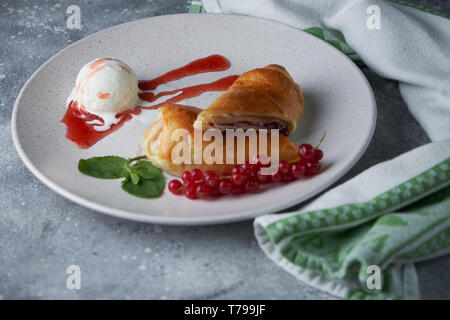 In Scheiben geschnittene Hausgemachte berry Strudel mit frischen rote Johannisbeere Beeren und Puderzucker auf einem alten Hintergrund auf einer Platte mit Eis pic serviert. Stockfoto