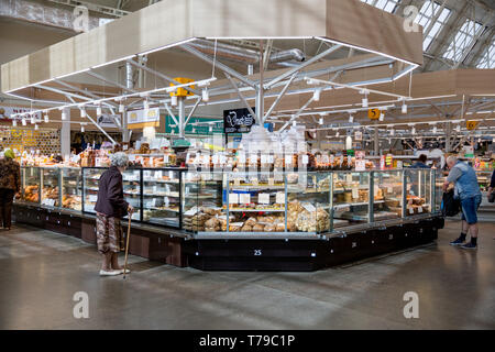 Stadt Riga, Lettland Republik. Alte Frau schaut zu Produkten. Der zentrale Markt mit den Kassierern, wo Völker Essen kaufen. Am 29. April. 2019 Reisen Foto. Stockfoto