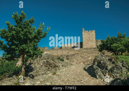 Gepflasterten Gehweg bis die Steigung in Richtung Mauer aus Stein und Turm von Marvao Castle. Eine mittelalterliche Weiler thront auf einem Felsen in Portugal. Stockfoto
