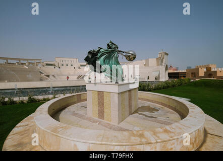 Katara Amphitheater Statue - Kraft der Natur II von Lorenzo Quinn mit Katara Dorf Amphitheater im Hintergrund. Stockfoto