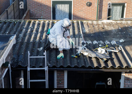 Professionelle Entfernung von Asbest. Männer in Schutzanzügen aus Asbestzement gewölbte Dachmaterialien Stockfoto