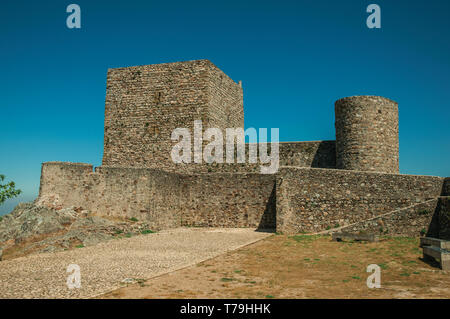 Kopfsteinpflasterbürgersteig zu Weg zu dicke Steinmauern und quadratischen Turm an der Marvao Castle. Eine mittelalterliche Weiler thront auf einem Felsen in Portugal. Stockfoto