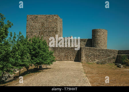 Weg mit Bäumen zu dicke Steinmauern und quadratischen Turm an der Marvao Castle. Eine mittelalterliche Weiler thront auf einem Felsen in Portugal. Stockfoto