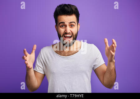 Junge wütend bärtiger Mann drückt seine negativen Emotionen, in einem Streit mit jemand, isolierte blauen Hintergrund, Stockfoto