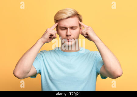 Stattlicher Mann mit geschlossenen Augen, leiden unter starken Kopfschmerzen, Tempel mit den Fingern zu berühren. bis Foto schliessen. Kerl ist auf seine Gedanken, man konzentriert Stockfoto