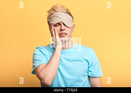 Junge traurig, unglücklich, der Mensch kann nicht aufwachen, morgens aufstehen. Kerl will nicht zur Arbeit zu gehen. Isolierte gelben Hintergrund Stockfoto