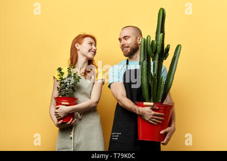 Lustig, glücklich, junger Mann und Frau mit Blumen und bei jedem anderen suchen. liebevolles Paar beim Gartenbau, Blumen. Glück Stockfoto