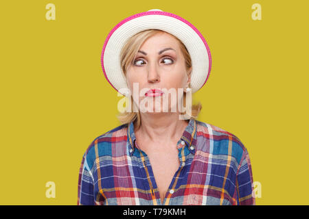 Closeup Portrait von Crazy crosseyed stilvolle reife Frau im lässigen Stil mit weißen Hut stehend, gekreuzte Augen und suchen mit lustigen Gesichtsausdruck. Stockfoto