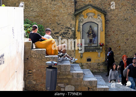 Touristen sitzen auf Schritte, die von der Statue von St. George, das Heiligtum am Eingang Castelo de Sao Jorge in Lissabon Schloss in Lissabon Portugal Europa EU-KATHY DEWITT Stockfoto