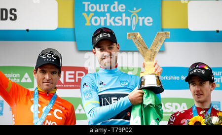 Tour de Yorkshire Sieger Team Ineos' Christopher Lawless (Mitte) feiert mit der Trophäe neben den zweiten Platz das CCC Team Greg Van Avermaet (links) und dritten Platz Team Ineos' Edward Dunbar (rechts) nach Stufe 4 der Tour de Yorkshire. Stockfoto