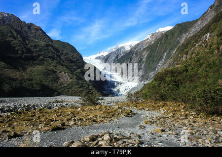 Blick auf den Franz Josef Gletscher, felsigen Aufstieg mit einigen grünen Vegetation auf beiden Seiten, an der Westküste der neuseeländischen Südinsel. Stockfoto