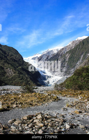 Blick auf den Franz Josef Gletscher, felsigen Aufstieg mit einigen grünen Vegetation auf beiden Seiten, an der Westküste der neuseeländischen Südinsel. Stockfoto