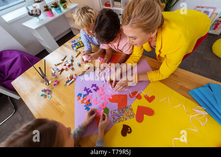 Klassenzimmer eingerichtet. Schüler Gefühl beteiligt, während die Schmetterlinge für Klassenzimmer Dekoration mit dem Lehrer Stockfoto