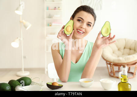 Junge Frau, die nährende Maske mit Avocado in der Küche Stockfoto