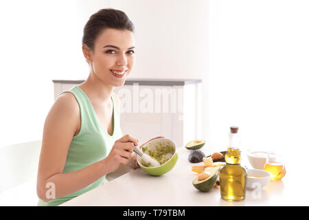 Junge Frau, die nährende Maske mit Avocado in der Küche Stockfoto