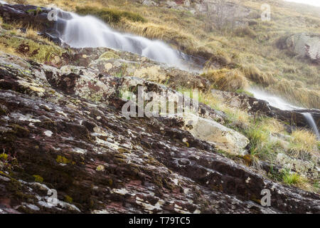 Niedrige Perspektive, Langzeitbelichtung, Zusammensetzung der Sprung Wasserfall der malerischen Mönch auf alten Berg, die Kaskadierung der sonnendurchfluteten Dark Red Rocks Stockfoto