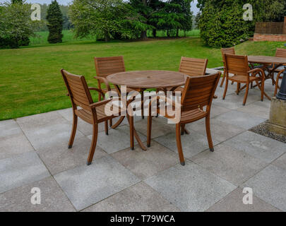 Holztisch und Stühlen auf einem slabbed Terrasse mit schönen Rasenflächen und eine Strukturansicht. Stockfoto