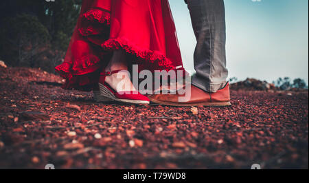 Paar mittleren Alters mit Füßen closeup in Rot Leder Schuhe und rote Rüschen Kleid bei Erreichen für Kiss Stockfoto