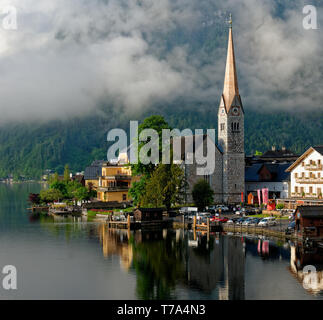 Am frühen Morgen geschossen von der Evangelischen Kirche in Hallstatt (Evangelische Pfarrkirche Hallstatt) und einem See Reflexion mit niedrigen Wolken im Hintergrund Stockfoto