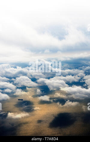 Wolken aus einem Fenster eines kommerziellen Ebene mit Blick auf das Meer und einige Schiffe über das Meer. Stockfoto