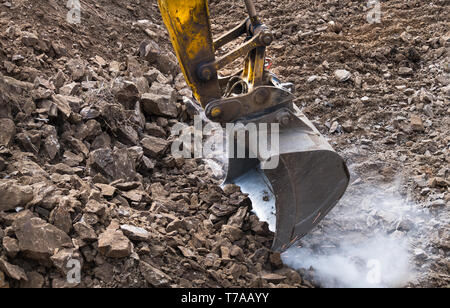 Arbeiten Bagger Schaufel. Funkenbildung. Staubige Baustelle. Digger Maschine. Aushubarbeiten. Power Schaufel bewegen Erde und Steine. Earth mover Schaufel. Stockfoto
