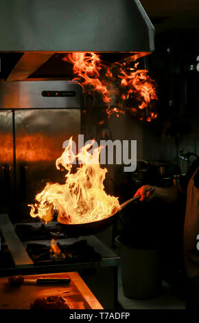 Cook Holding lodernde Flammen von Pan Pan und steigende Stockfoto