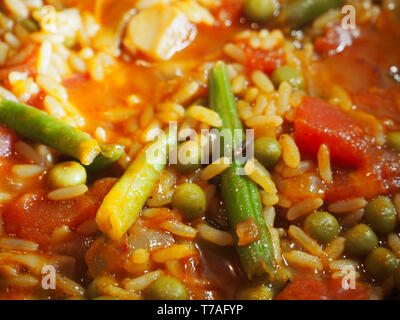 Vegane Paella aus Reis, Erbsen, Tomaten und Bohnen Stockfoto