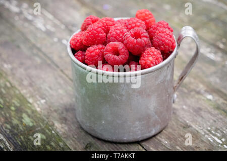 Vintage rustikalen Becher voller Himbeere Beeren auf Holztisch. Stockfoto