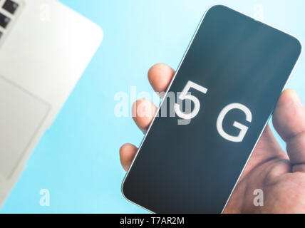 5G-Technologie, Hand mit Handy mit 5-g-Konzept, Internet auf mobilen Smart Phone und auf blauem Hintergrund. Stockfoto
