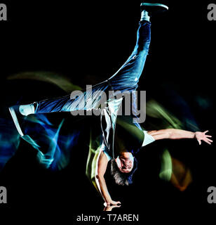 Ein chinesischer Junge Mann hip hop Break Dancer tanzen auf schwarzen Hintergrund mit Geschwindigkeit Licht Malerei Wirkung Bewegungsunschärfe isoliert Stockfoto